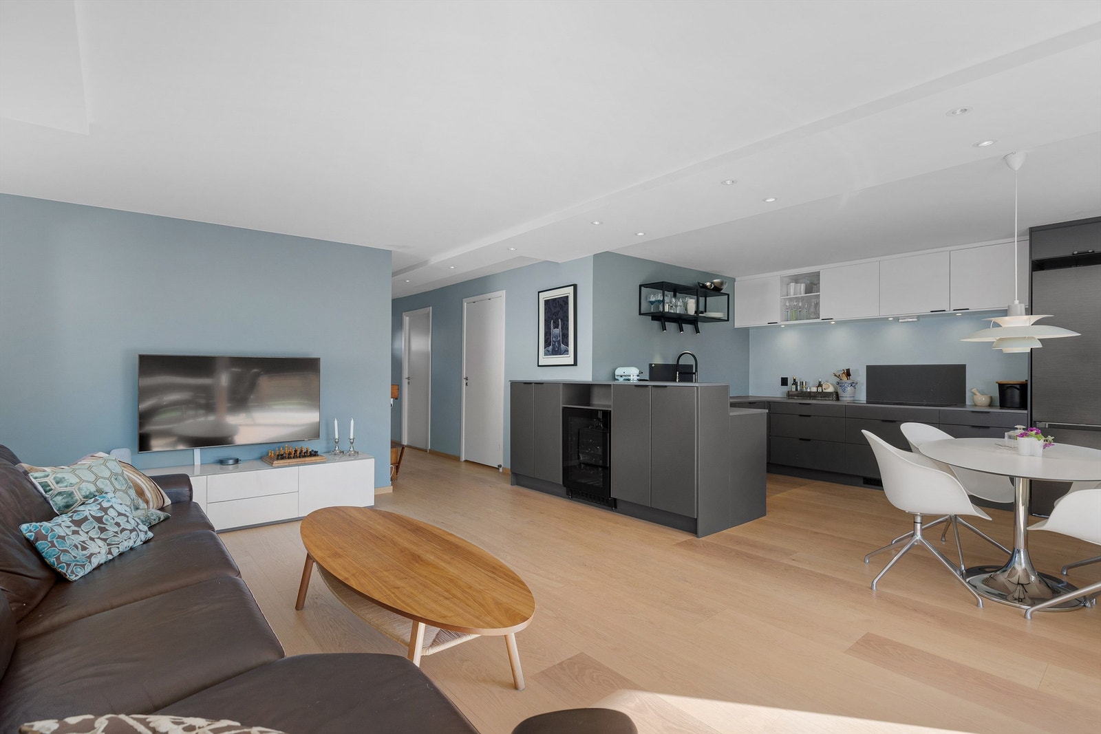 Den praktiske "halvveggen" mellom stue og kjøkken skjermer godt og gir en naturlig avgrensing av sonene. I tillegg er det ekstra lagringsplass, med skap på begge sider av "veggen" Galleribilde