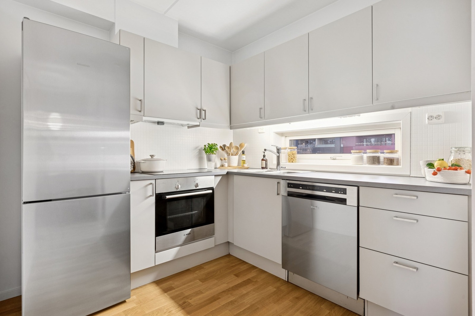 Kjøkkenet har en delvis åpen løsning mot stue, som gir en sosial og funksjonell planløsning. Innredningen har glatte fronter og laminert benkeplate. Det er god skap- og benkeplass, samt benkebelysning og stikkontakter under overskap. Galleribilde