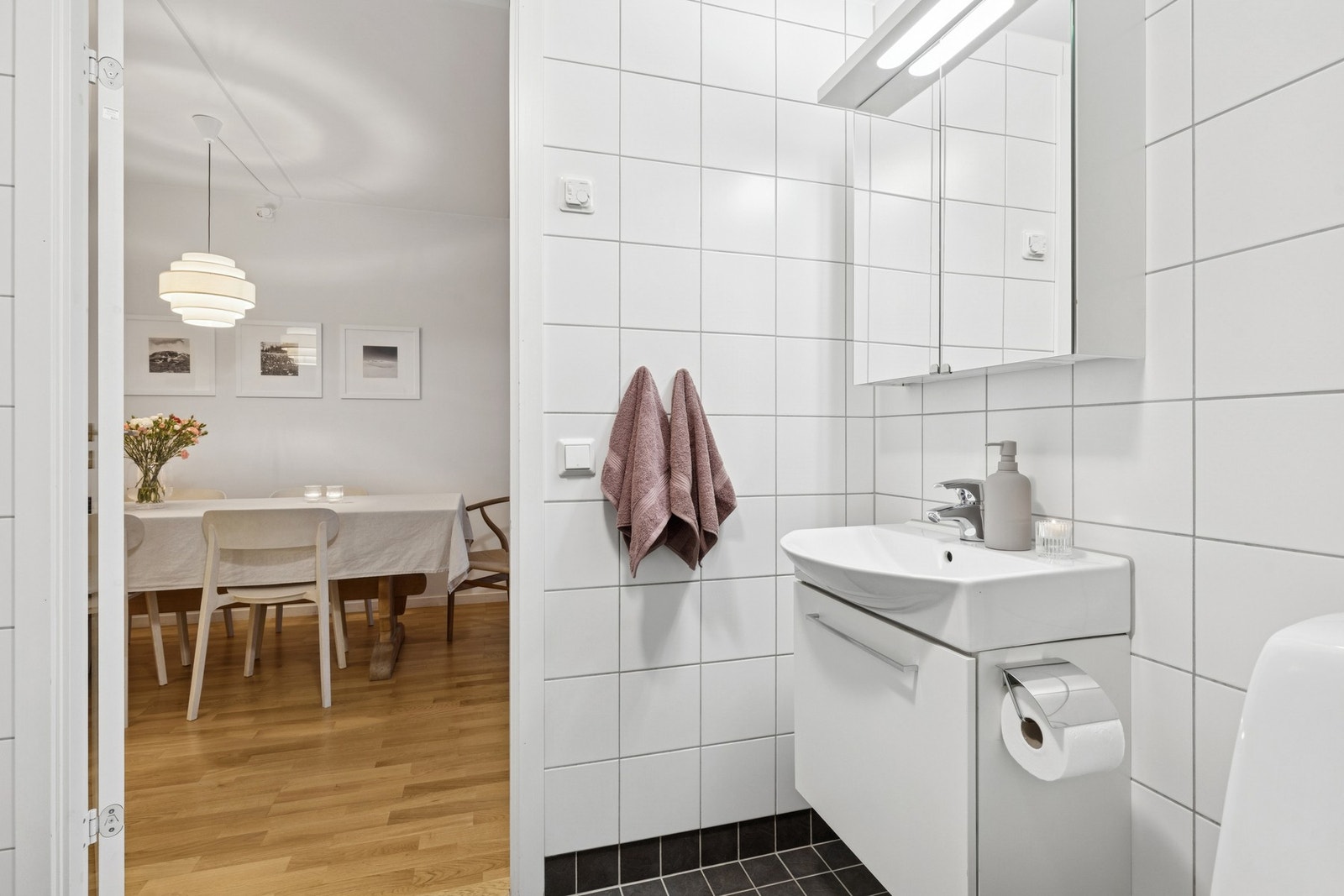 Rommet inneholder vegghengt toalett, vegghengt servantinnredning med heldekkende servant, speilskap med belysning og stikkontakt, samt dusjhjørne med innfellbare glassdører. Galleribilde