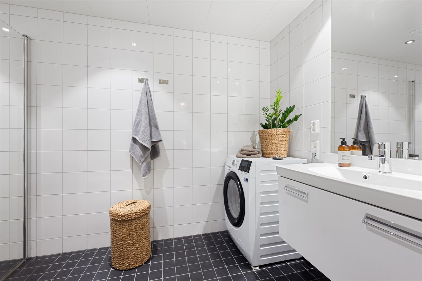 Kombinert bad og vaskerom med prefabrikkert baderomskabin. Rommet er helfliset med fliser på gulv og vegger og i himlingen er det montert downlights. Det er opplegg for vaskemaskin og varme i gulvet. Galleribilde