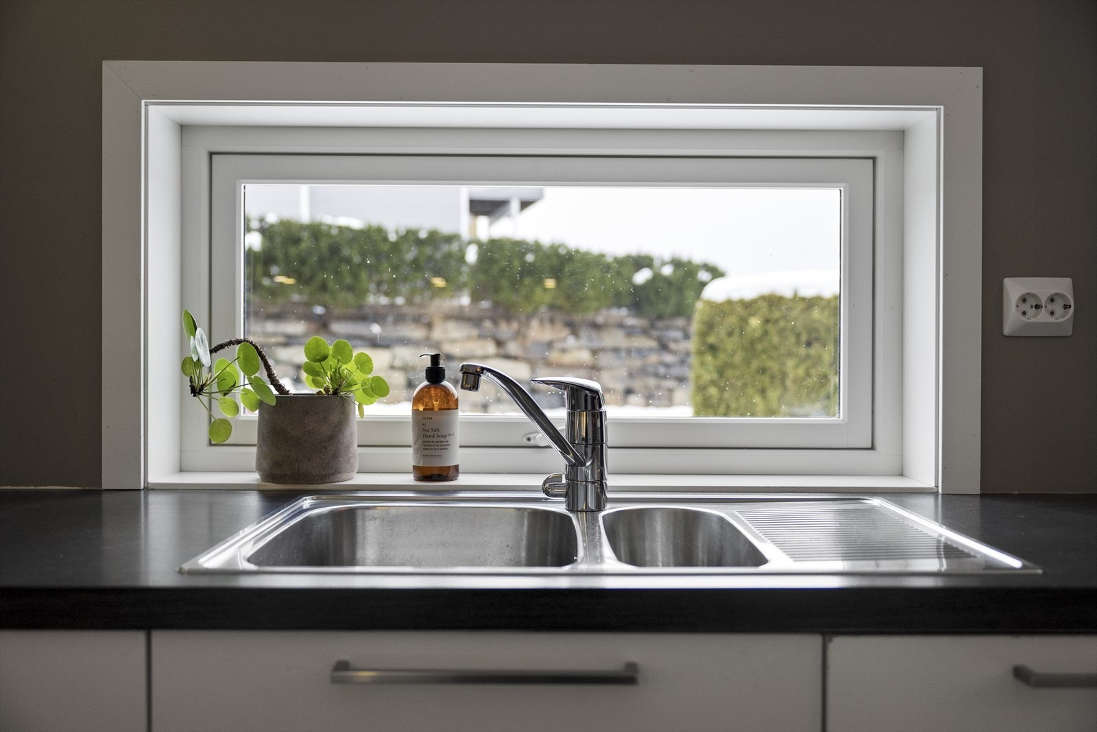 Kjøkkenvinduet gir utsyn mot innkjørsel og hage på husets forside. Galleribilde