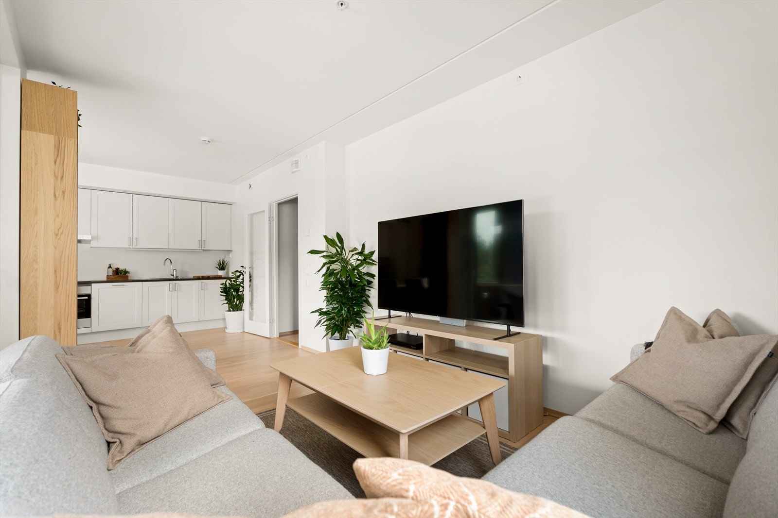 Plass til sofagruppe i stuen skaper et komfortabelt oppholdsrom med enkel tilgang til kjøkkenet. Galleribilde