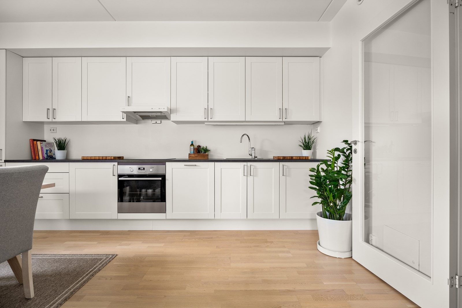 Kjøkkenet har integrert kjøl/fryseskap, komfyr, induksjonstopp, oppvaskmaskin og en avtrekksvifte med avtrekk ut. Galleribilde