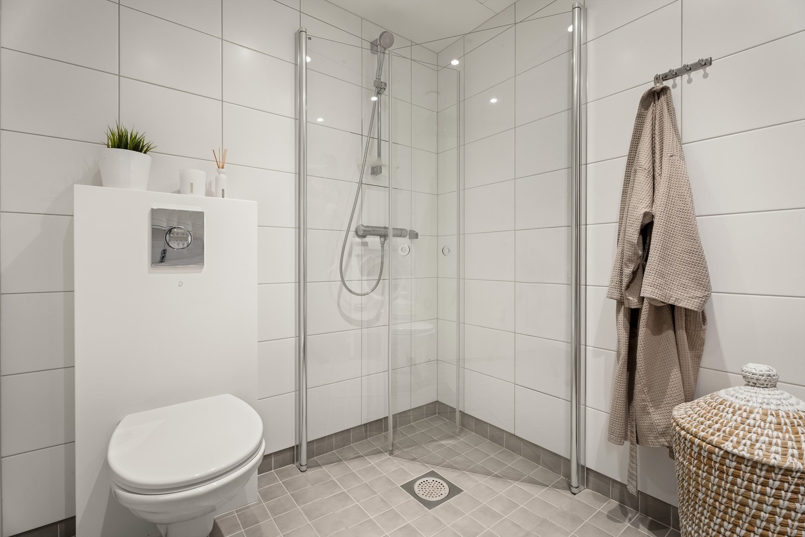 Dusjhjørne med glassdører og vegghengt toalett gir effektiv bruk av baderommet. Galleribilde