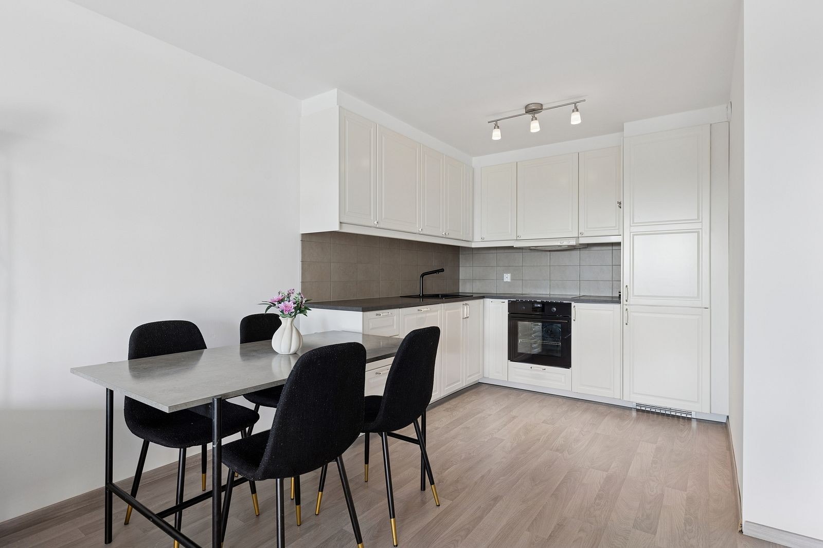 Lyst og pent kjøkken med spisebord i forlengelse Galleribilde