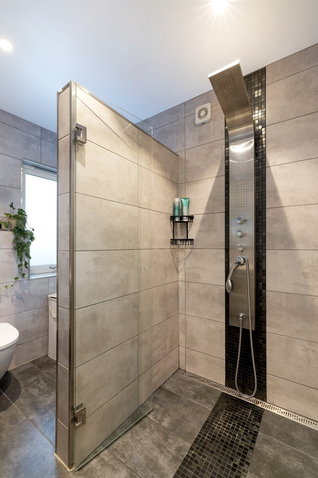 Badet har inngang både fra gang og fra hovedsoverom og består av dusjnisje, vegghengt toalett og servant med underskuffer og overspeil. Galleribilde