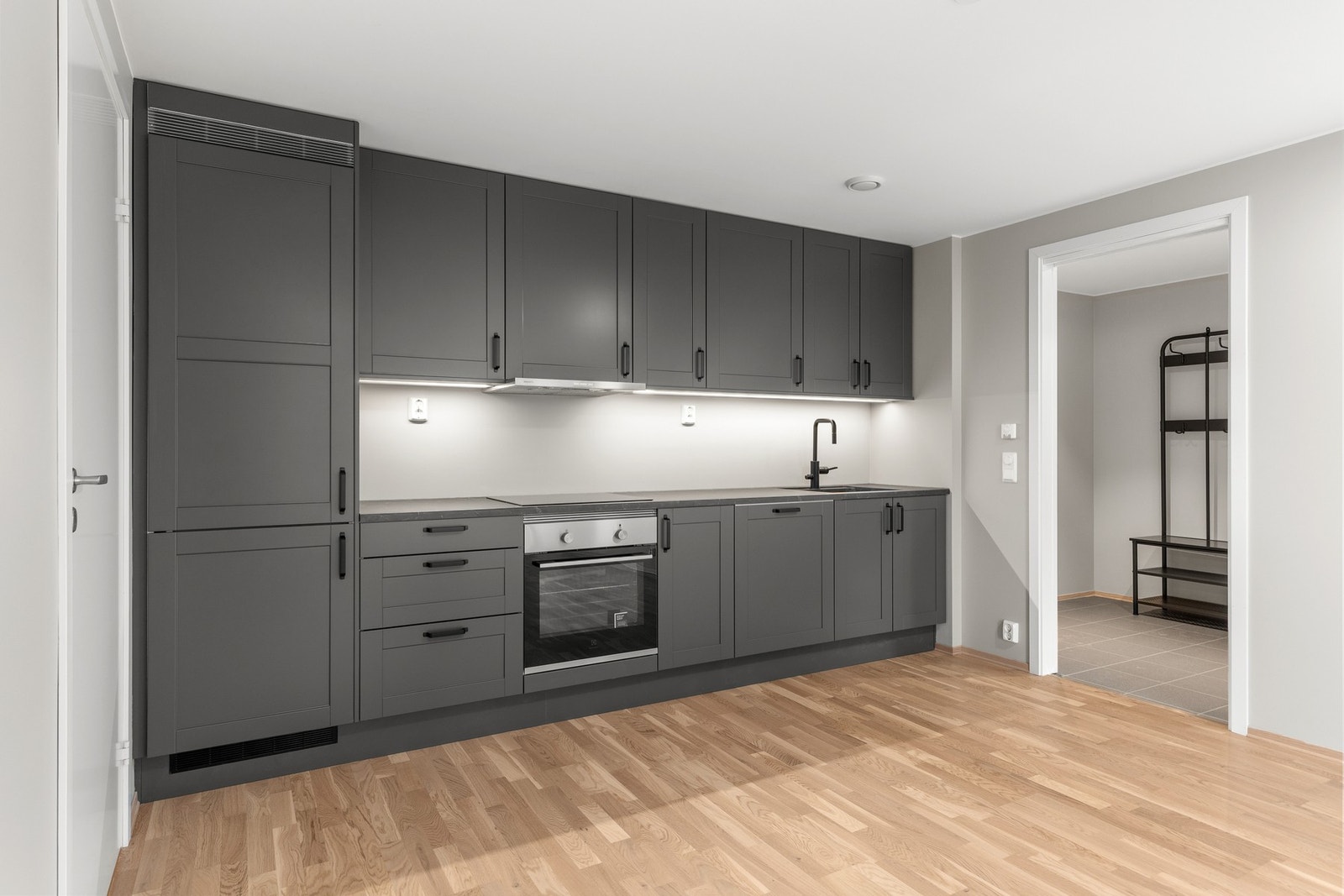 Kjøkkeninnredningen er av glatte fronter i en moderne utførelse samt benkeplate av laminat. Galleribilde