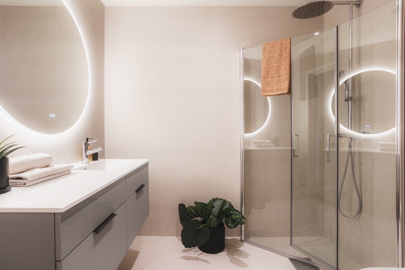 Delikat familiebad med dusjhjørne, servant med oppbevaring og moderne fliser. Galleribilde