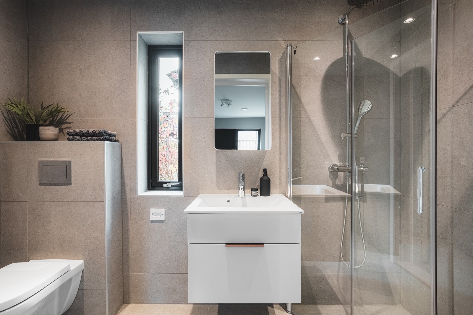 Bad med inngang fra rommet er utstyrt med dusjhjørne, servant med oppbevaring og vegghengt toalett. Det er også opplegg for vaskemaskin. Galleribilde