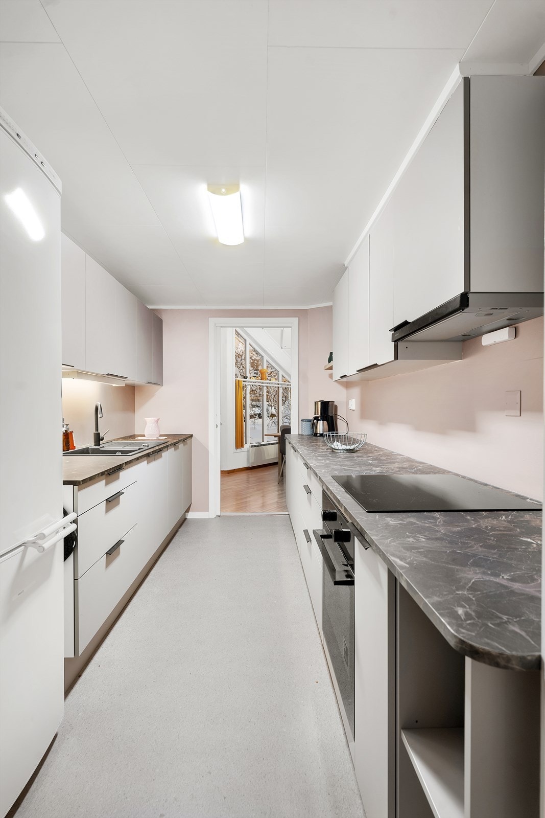 Flott kjøkken tilknyttet gjesteleiligheten/hybelen, utført i lyse overflater og delvis integrerte hvitevarer. Galleribilde