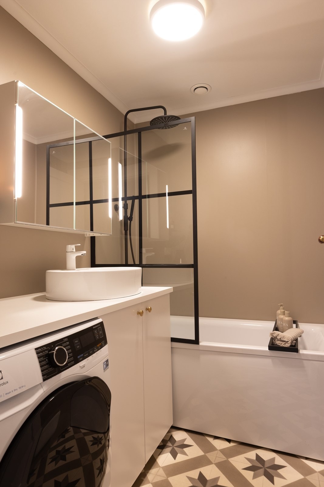 Badet er innredet med badekar med dusjløsning og opplegg for vaskemaskin. Galleribilde