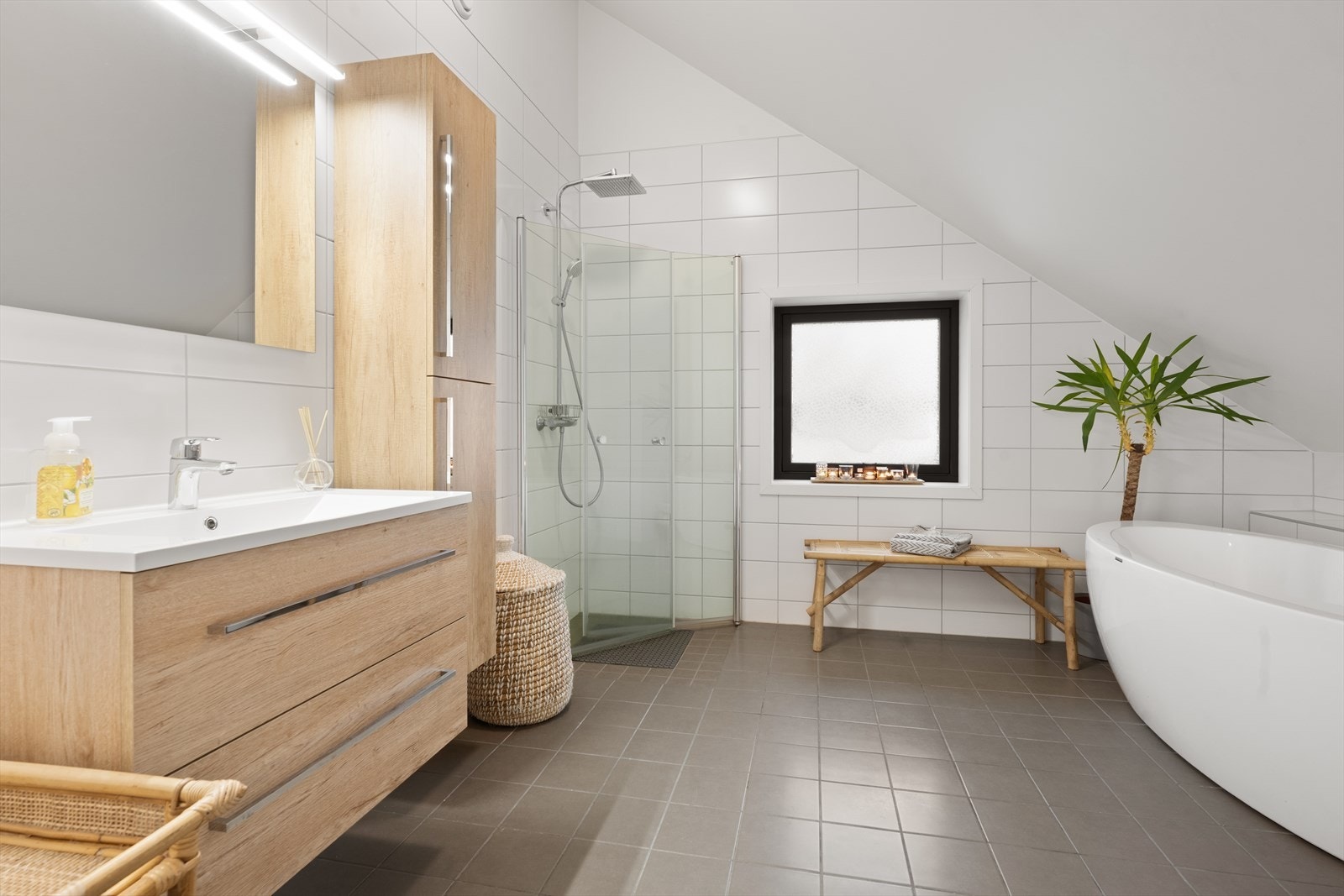 Stort og delikat bad innredet med servant i skuffeinnredning, stort speil, dusj med innfellbare dusjdører, badekar og vegghengt toalett. Galleribilde