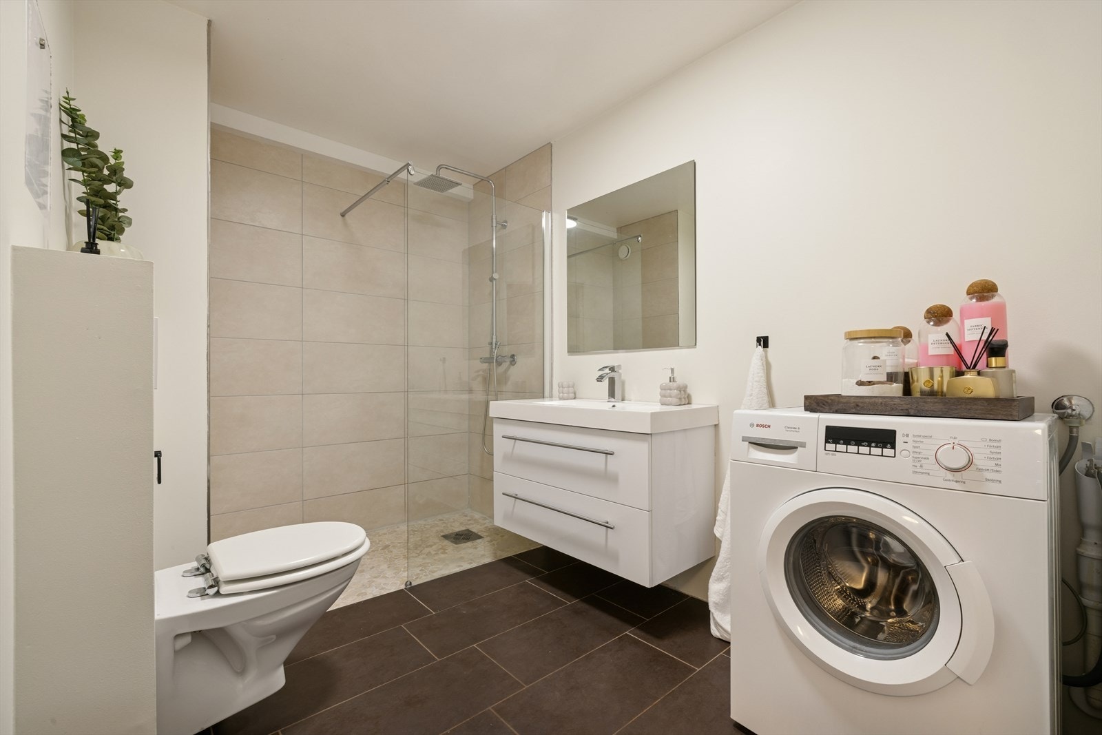 Pent og funksjonelt bad med flislagte overflater, dusjhjørne med glassvegger og god gulvplass. Galleribilde