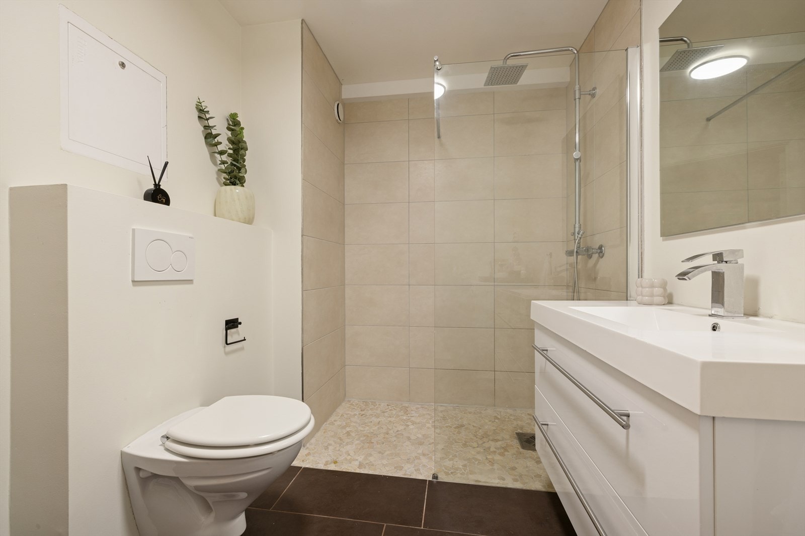 Romslig dusjsone med flislagte vegger, moderne dusjgarnityr og sluk i gulv. Galleribilde