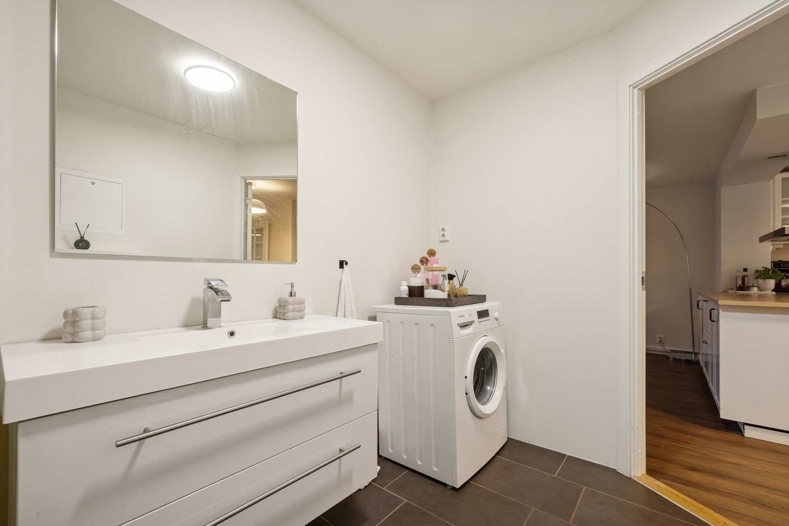 Baderommet er innredet med servant med underskuffer, servantbatteri, speil, vegghengt toalett og flislagt gulv med varmekabler. Galleribilde