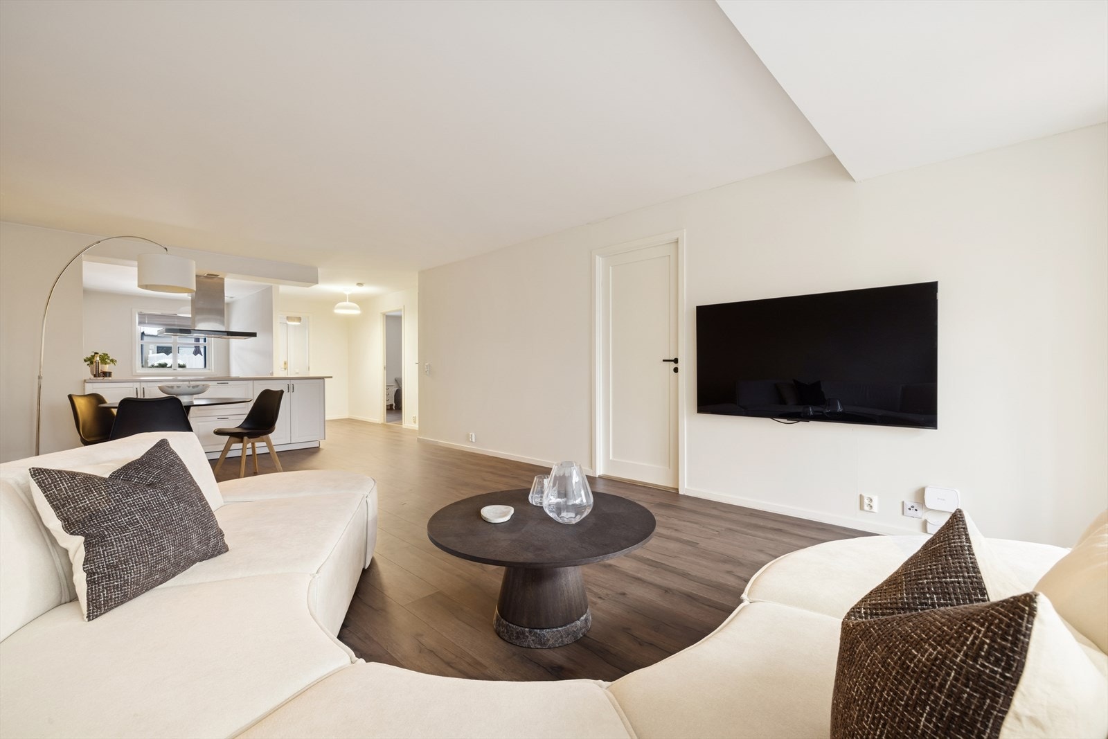 Stilrent oppholdsrom med moderne linjer, gjennomgående gulvflater og en åpen løsning som gir et eksklusivt og luftig uttrykk. Galleribilde