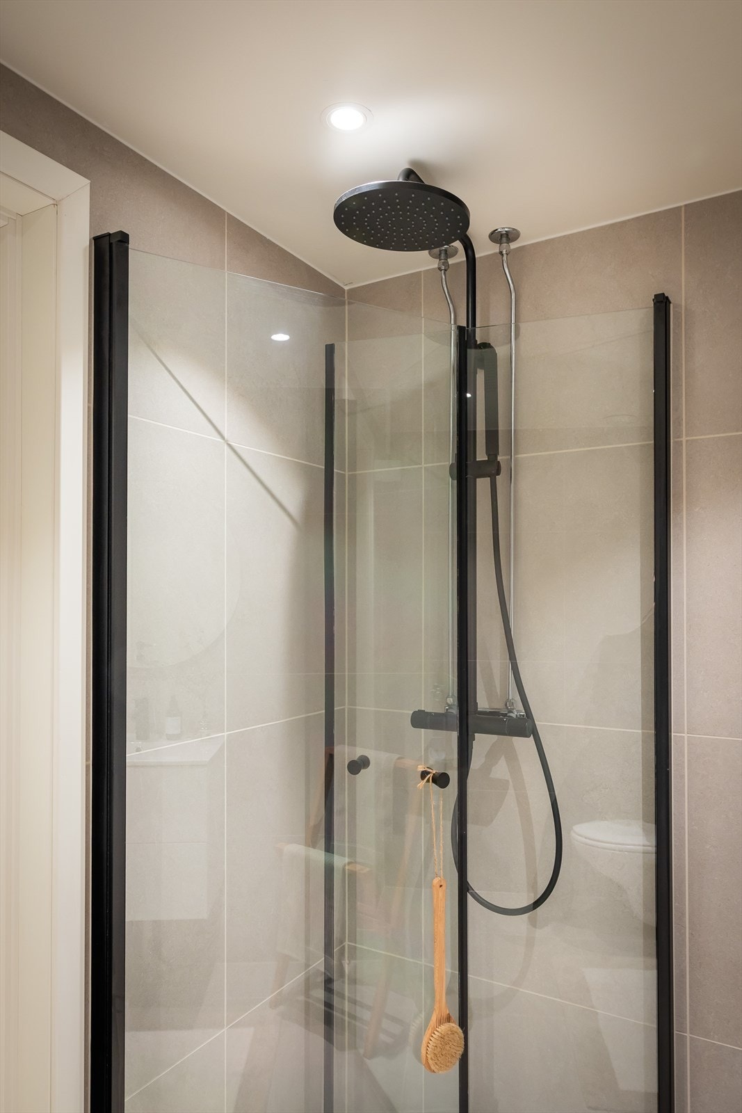 Lekkert nytt dusjhjørne med svingbare glassdører, regnfallsdusj og hånddusj med sorte detaljer. Galleribilde
