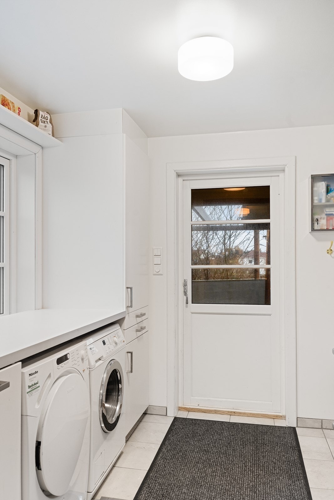 Praktisk vaskerom med flislagt gulv og egen biinngang Galleribilde