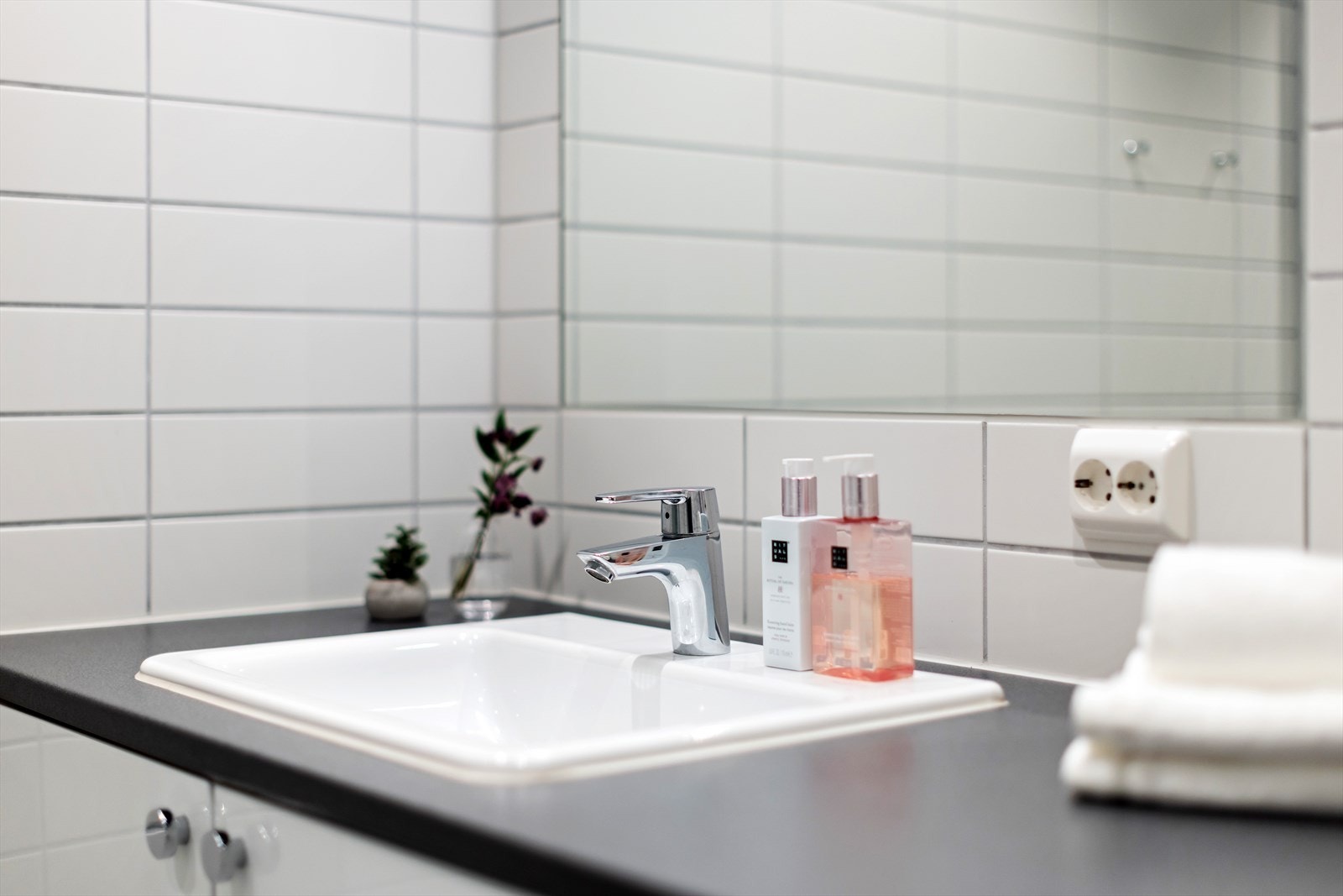 Badet er innredet med servantinnredning med skap og speil, vegghengt toalett, dusj med glassdører samt opplegg for vaskemaskin. Galleribilde