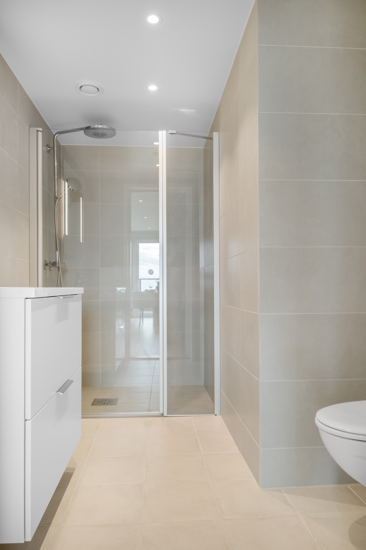 Flislagt bad med elektriske varmekabler i gulv. Rommet er innredet med vegghengt toalett, servant og dusj hjørne. Galleribilde