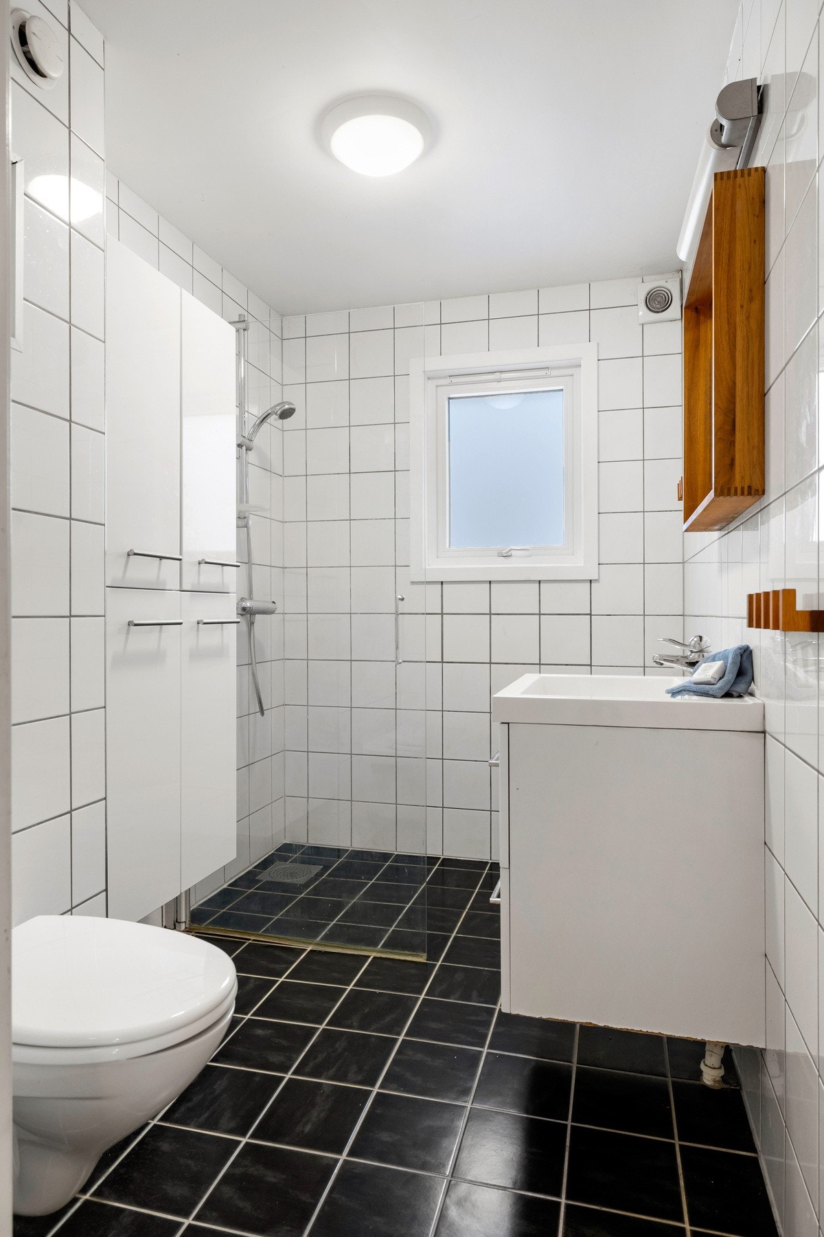 Badet i 1. etg fremstår som lyst og funksjonelt. Badet er innredet med servant med skuffer og speil, dusjhjørne med glassvegg og vegghengt toalett. Galleribilde