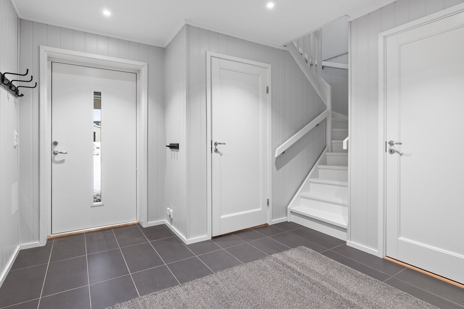 Flislagt gulv gir en praktisk og slitesterk overflate i entréen. Malt MDF-panel på veggene gir et rent og moderne uttrykk. Galleribilde