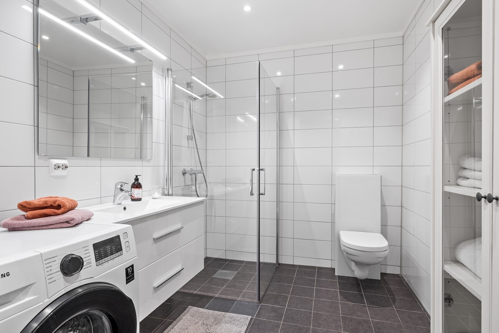 Flislagte vegger og gulv med elektriske varmekabler gir et moderne bad. Dusjnisje med glassdører sikrer enkel tilgang og ventilasjon er mekanisk. Badet har opplegg for vaskemaskin Galleribilde