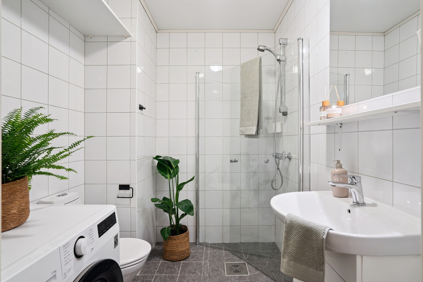 Bad med fliser på både gulv og vegger, romslig dusjløsning og opplegg for vaskemaskin og tørketrommel. Galleribilde