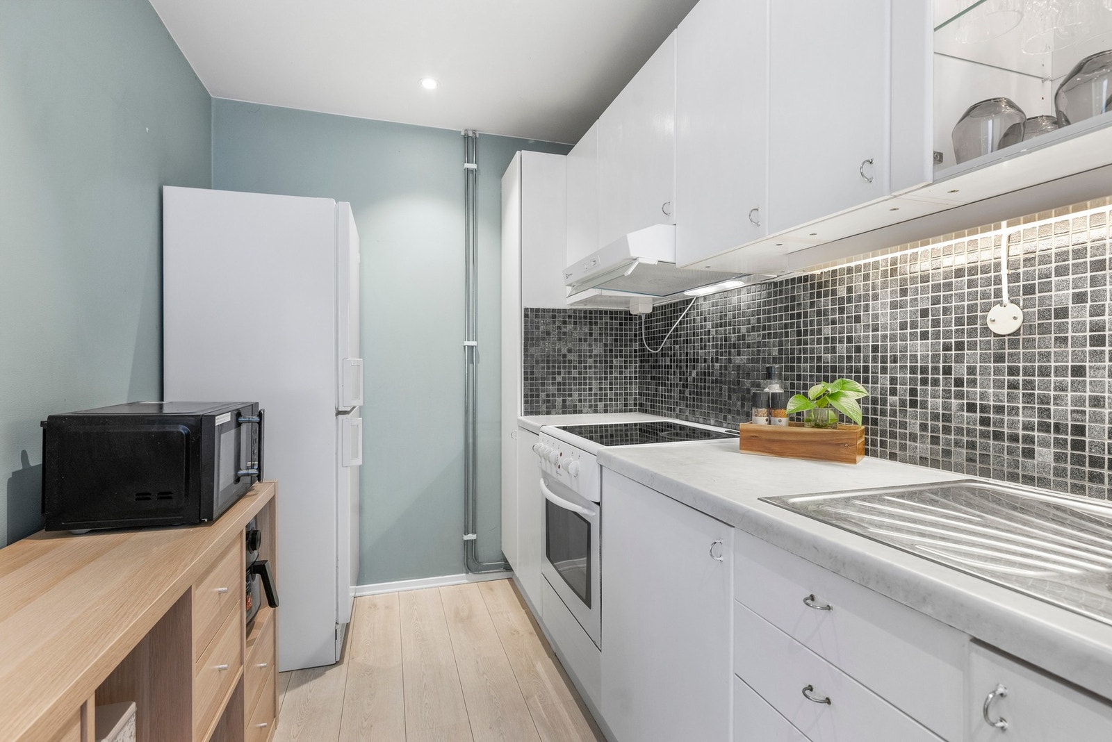 Kjøkkenet har en funksjonell innredning med glatte fronter og benkeplate i laminat Galleribilde