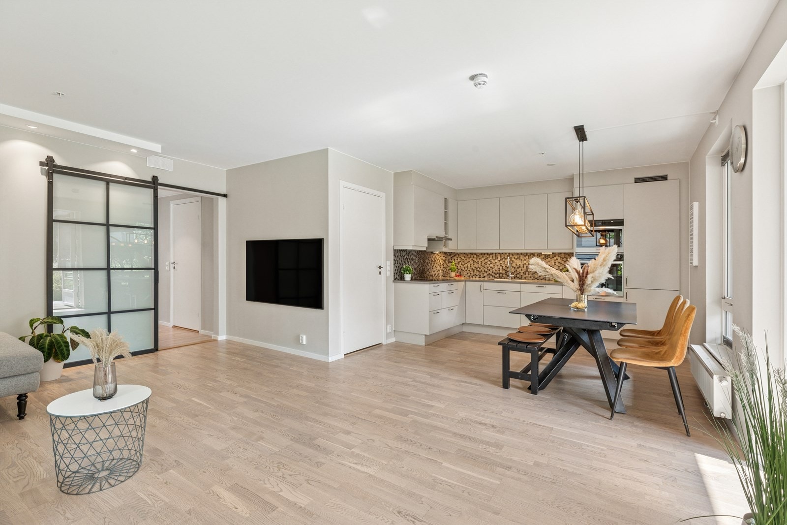 Åpen løsning mot kjøkkenet. Legg merke til skyvedøren mellom stue og gang i glass og svartmalt metall. Galleribilde