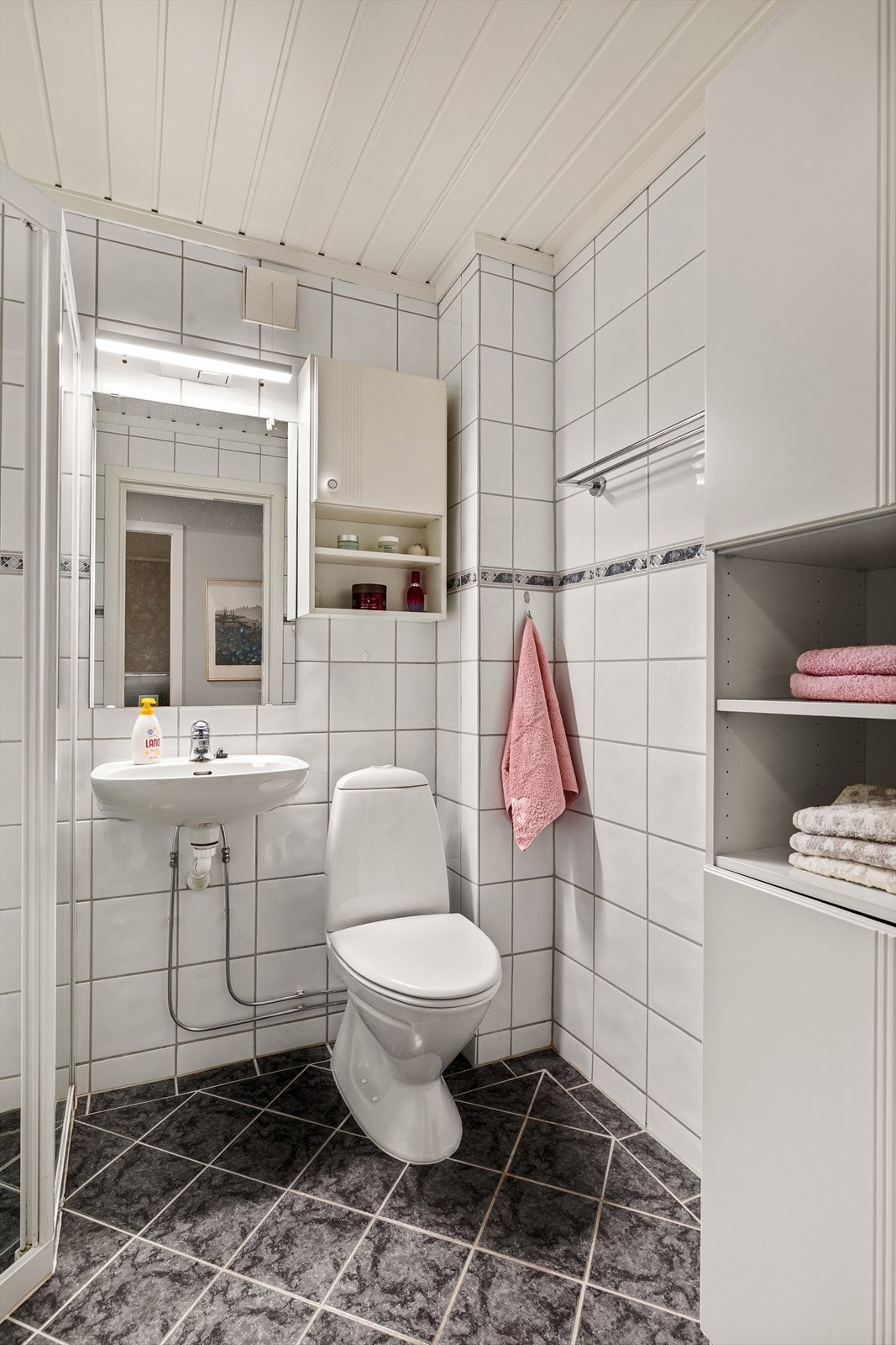 Badet inneholder dusjhjørne, servant, innredning, toalett og opplegg for vaskemaskin Galleribilde