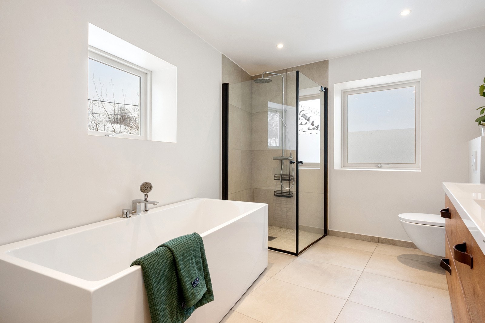 Dusjhjørnet er utført med mosaikkfliser på gulv, glassvegger, samt både hånd- og takdusj. Badet er i tillegg innredet med frittstående badekar med karmontert blandebatteri og hånddusj. Galleribilde