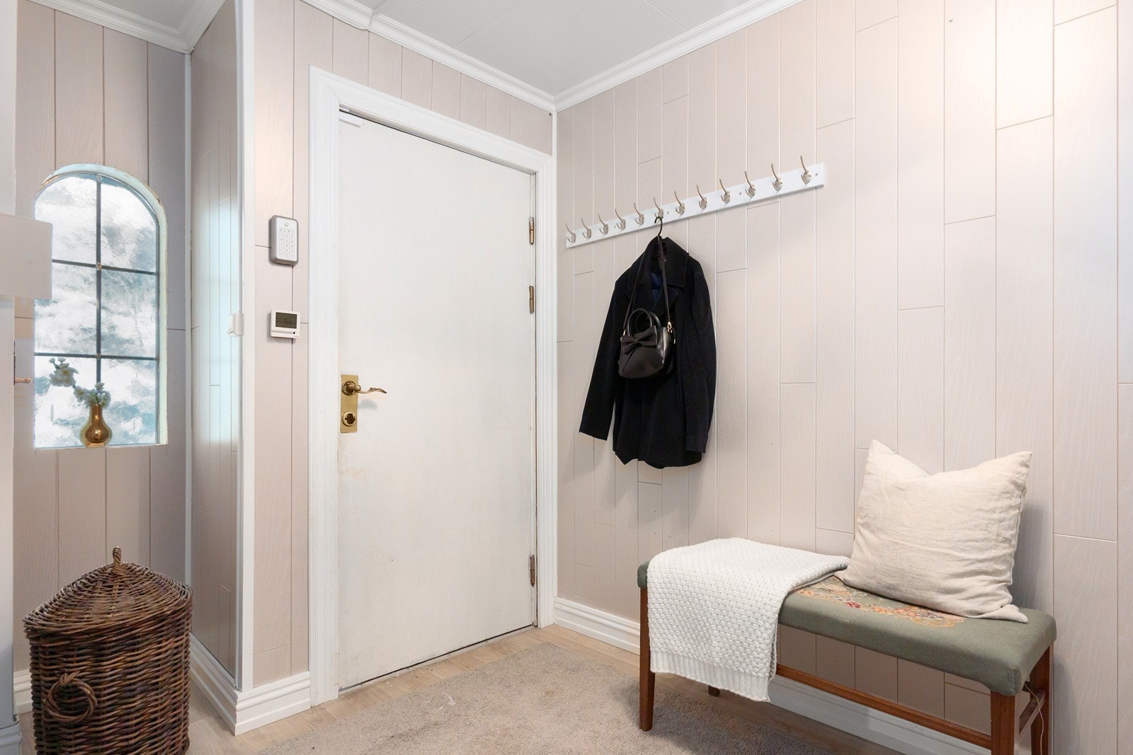 Vel innenfor er det knaggrekke for enkel oppheng av yttertøy, samt plass til sittebenk. Herfra leder en dør med glassfelt videre inn til en åpen hall. Galleribilde