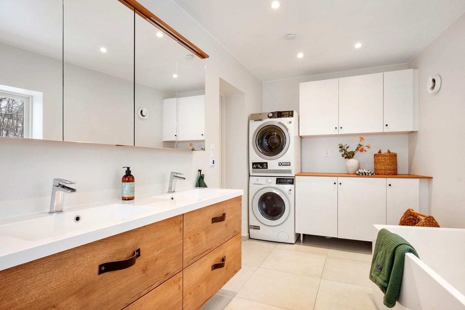Langs veggen er det opplegg for vaskemaskin og tørketrommel, med praktisk benkeplass og høyskap som gir gode oppbevaringsmuligheter. Galleribilde