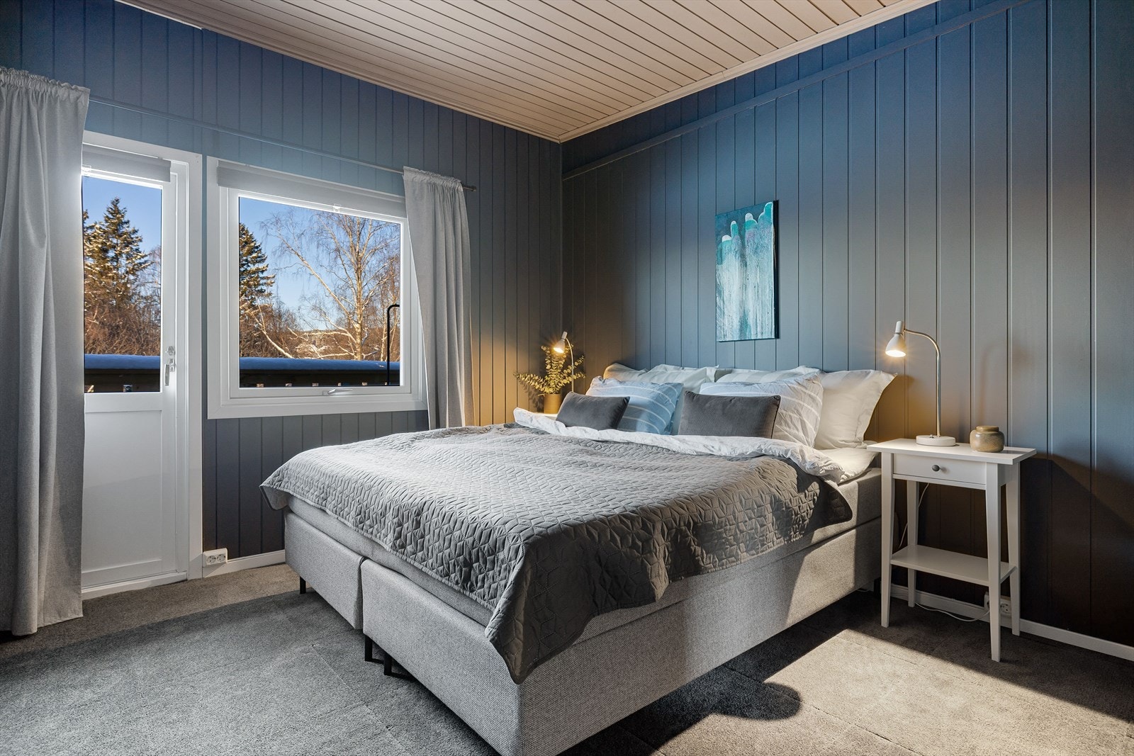 Boligen har et innbydende hovedsoverom med lunt teppegulv og overflater malt i en fin mørk blåfarge. Galleribilde