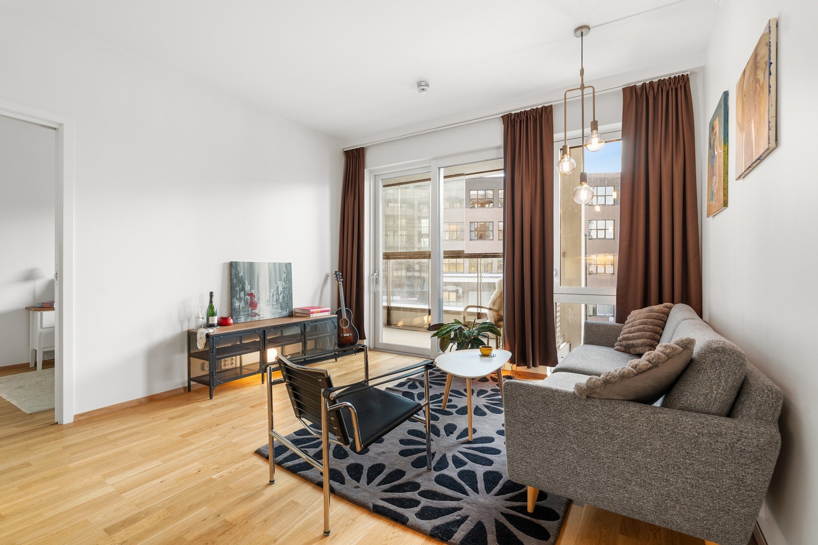 Romslig stue med utgang til romslig balkong som vender "riktig" vei. Vinduer fra vegg til tak gir godt med innslipp av naturlig lys. Foto: Krogstad og Nervik Galleribilde