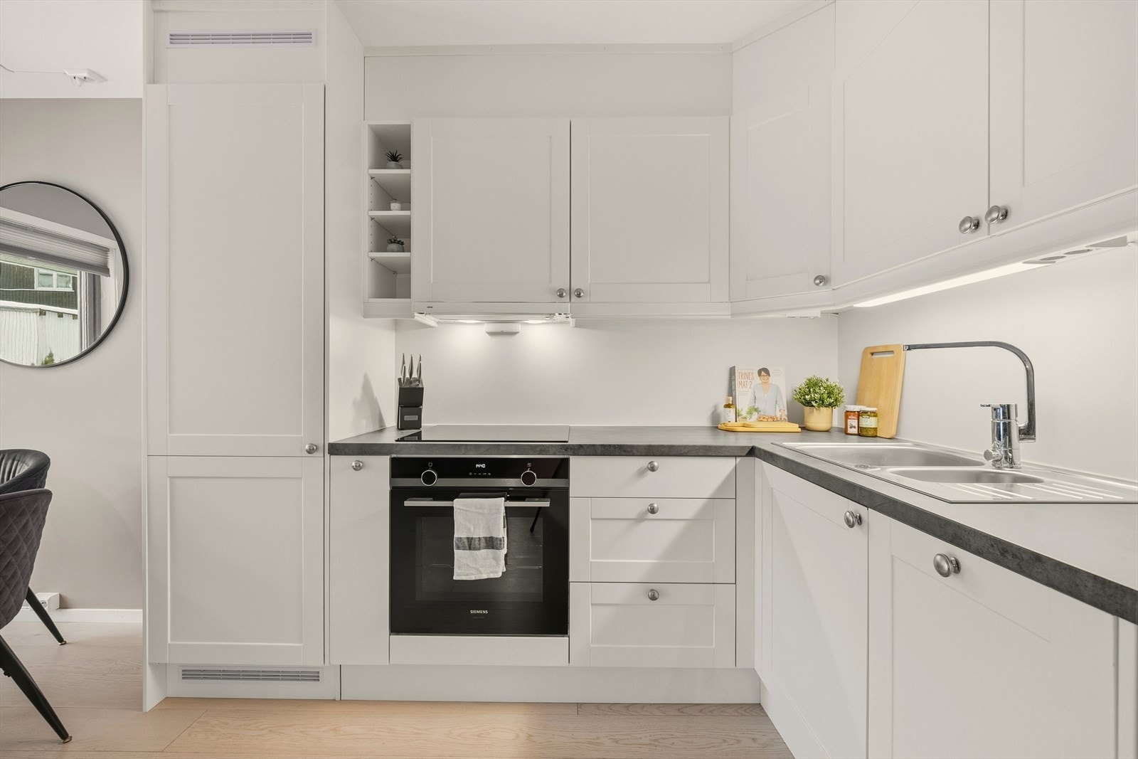 Kjøkkenet er utstyrt med integrerte hvitevarer som stekeovn, platetopp, kjøleskap og oppvaskmaskin Galleribilde