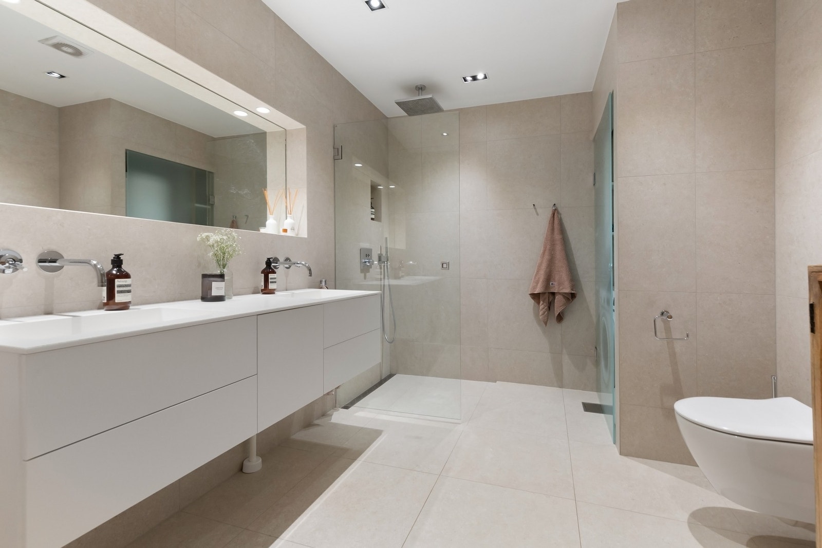 Innredning med to nedfelte servanter, veggmontert toalett, dusjvegger/hjørne og opplegg vaskemaskin. Galleribilde