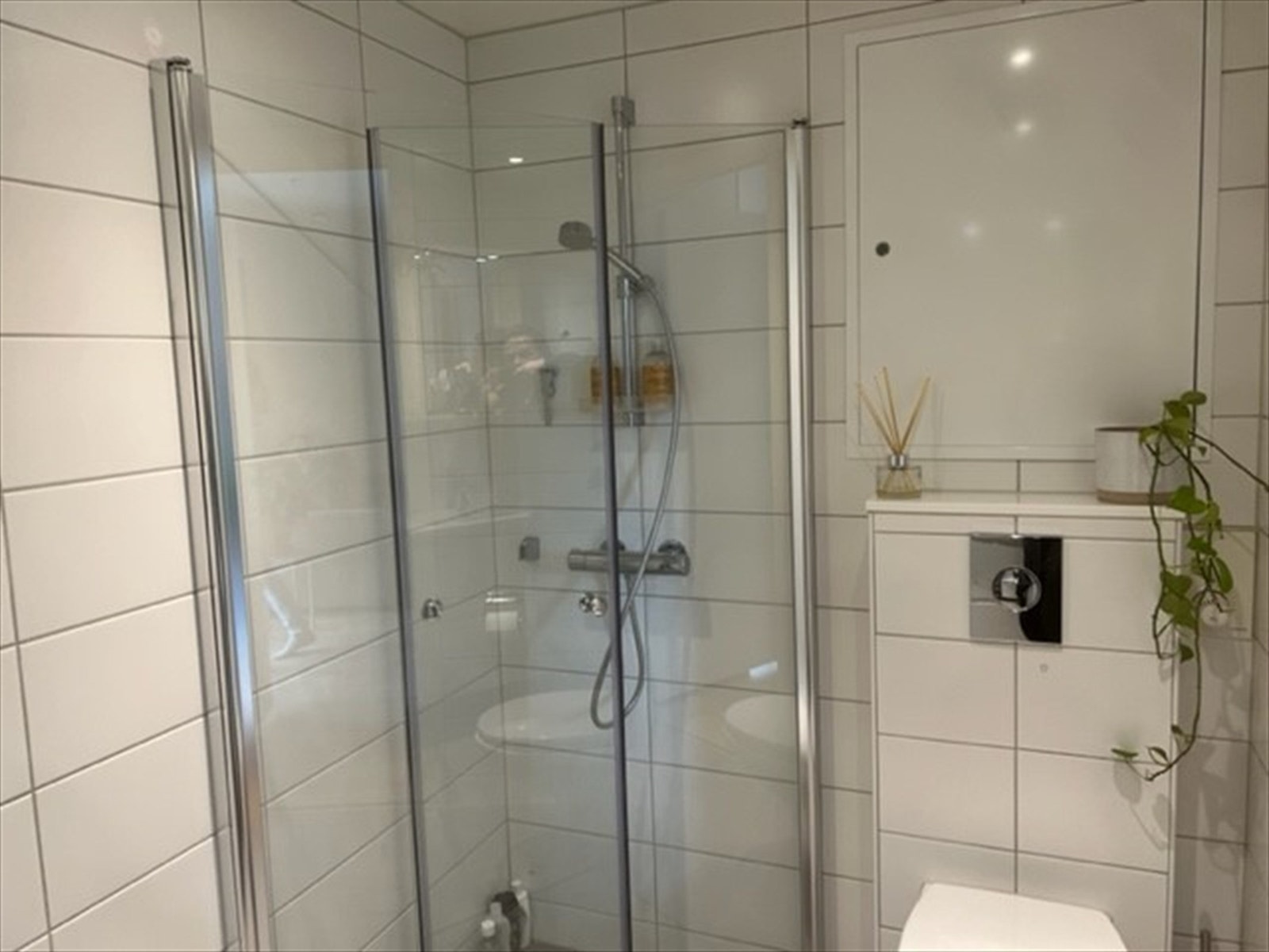 Toalett og dusj. Dusjdører i glass og vegghengt toalett. Galleribilde