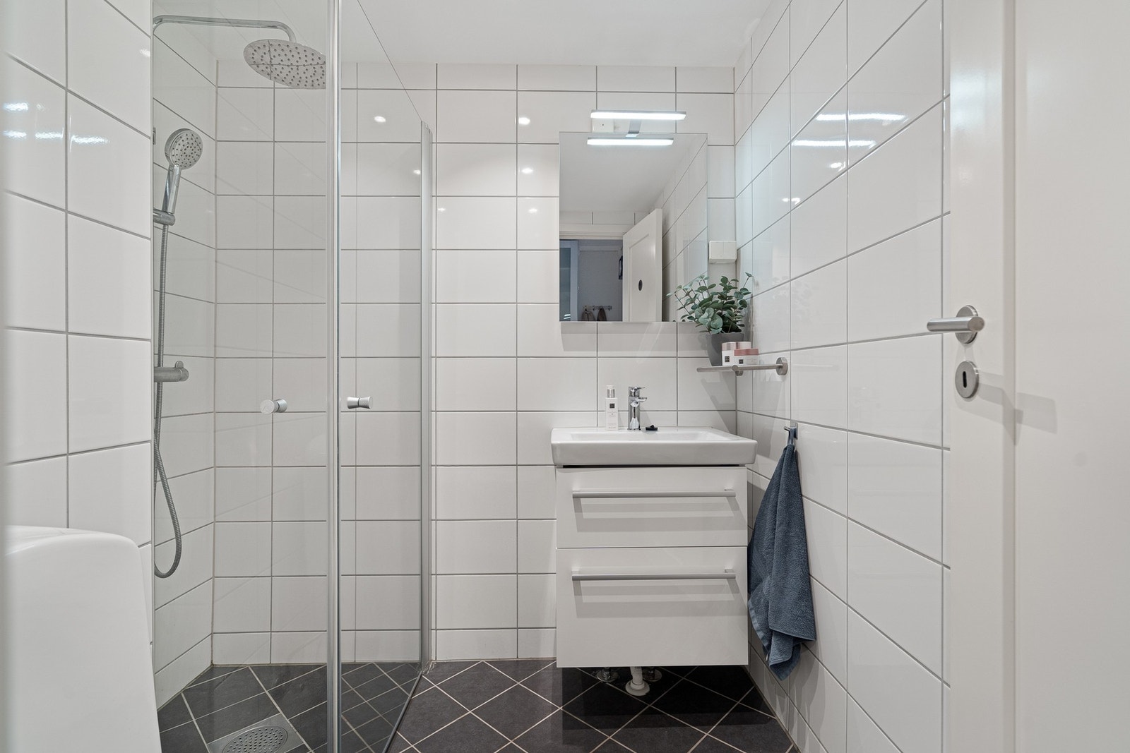 Badet er flislagt på gulv og vegger med malt, slett himling, og fremstår pent og funksjonelt. Galleribilde