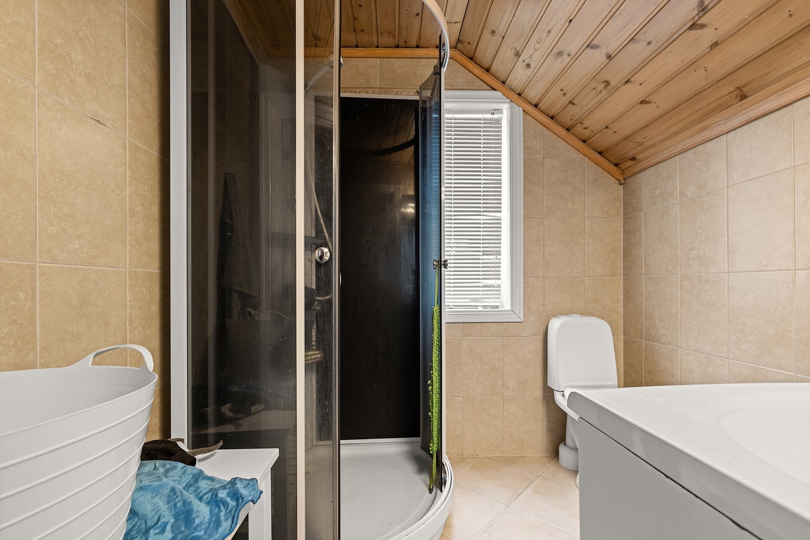 Flislagt bad med varmekabler i gulv. Badet er innredet med servantinnredning, speil, toalett og dusjkabinett. Galleribilde