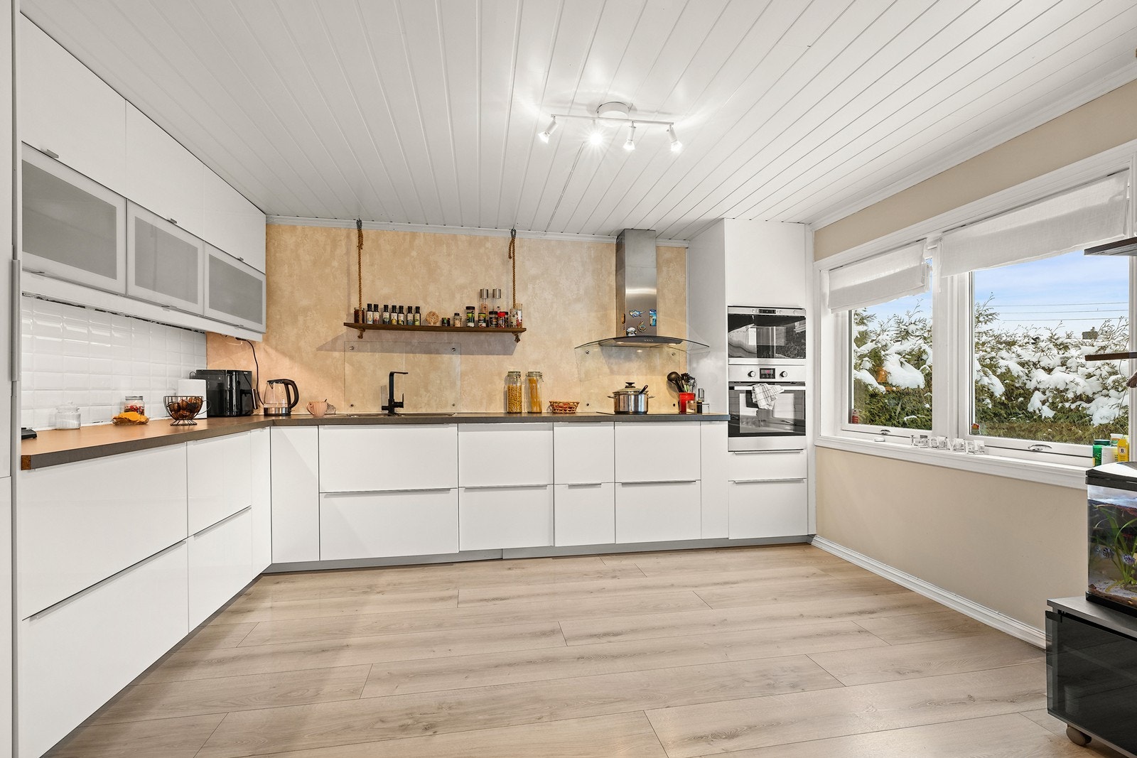 Delikat kjøkkeninnredning med hvite, glatte fronter og benkeplate av laminat med dobbel stålkum, som bærer et harmonisk samspill mellom eleganse og funksjonalitet. Galleribilde