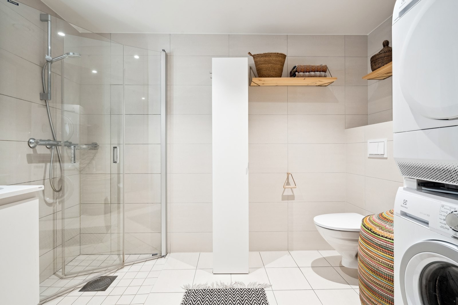 Her er badet utstyrt med dusjhjørne med innfellbare glassvegger, vegghengt wc og servantinnredning med underskap. I tillegg er det opplegg og plass til både vaskemaskin og tørketrommel Galleribilde