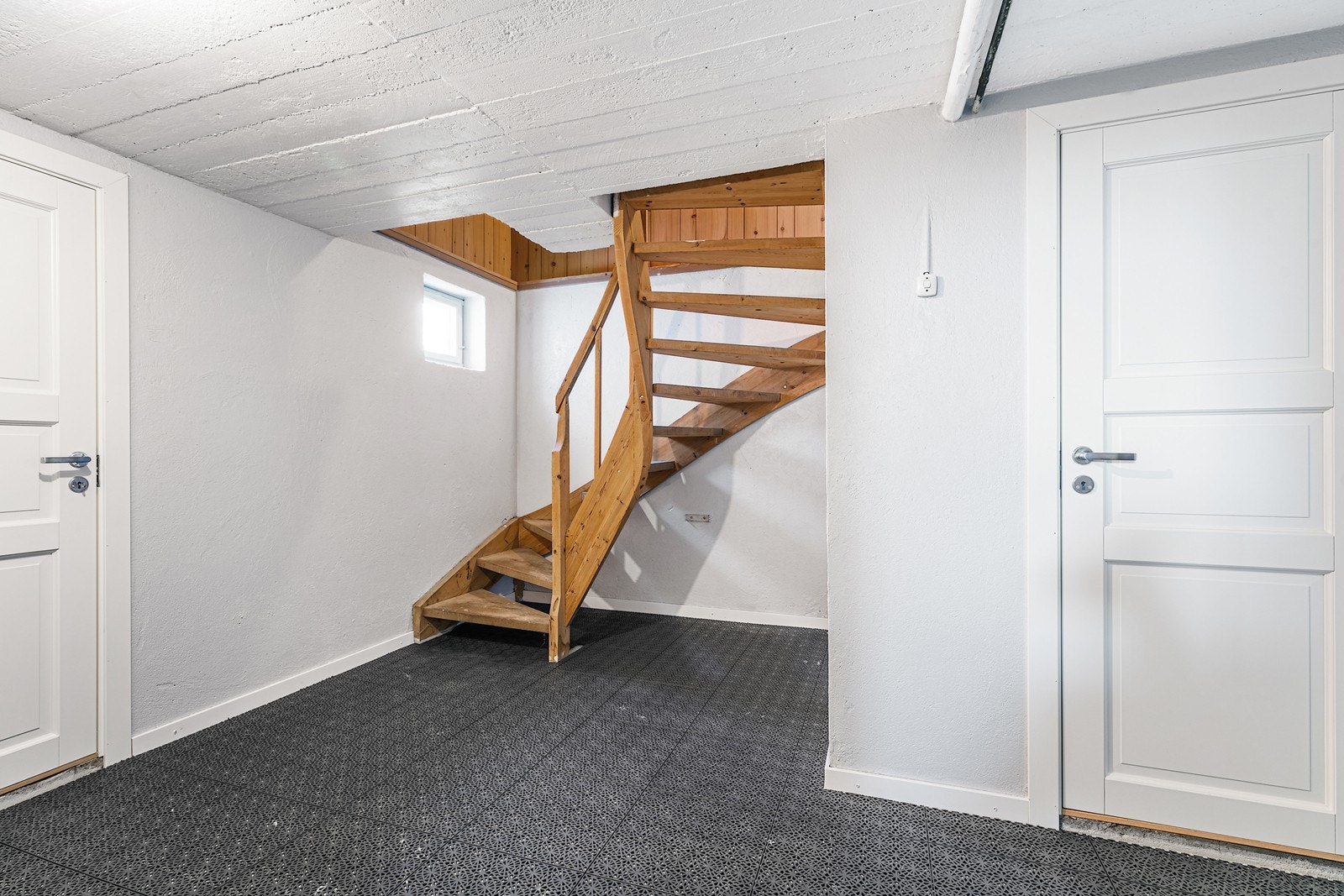 Lakkert tretrapp gir tilgang til underetasjen, hvor malte glatte dører gir et rent uttrykk. Galleribilde