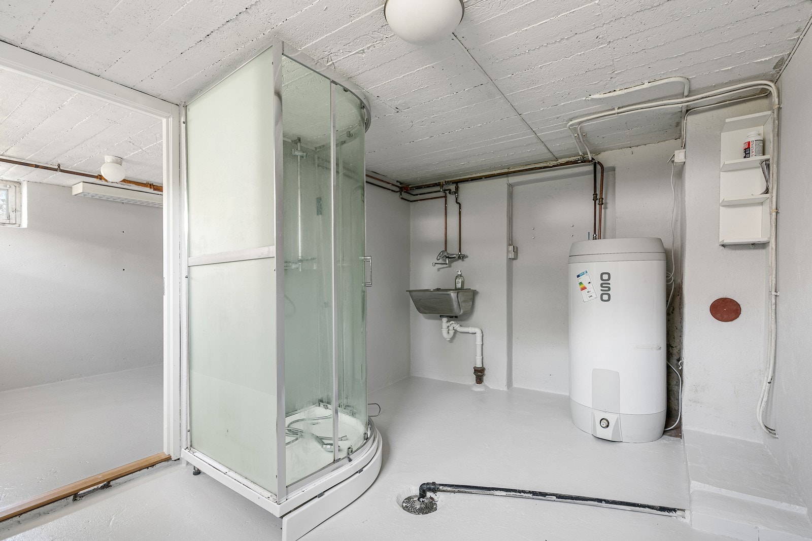 Vaskerommet er utstyrt med varmtvannsbereder og enkel servant. Det er malt gulv, vegger og tak, men mangler godkjent tettesjikt. Dusjkabinettet står bare løst på gulvet og er ikke koblet til. Galleribilde
