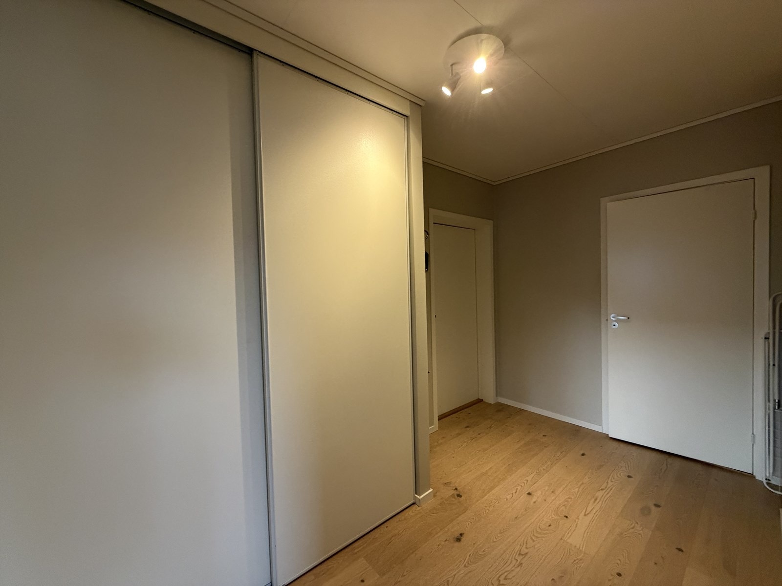 Her finner du et praktisk og plassbesparende integrert garderobeskap med skyvedører. Galleribilde