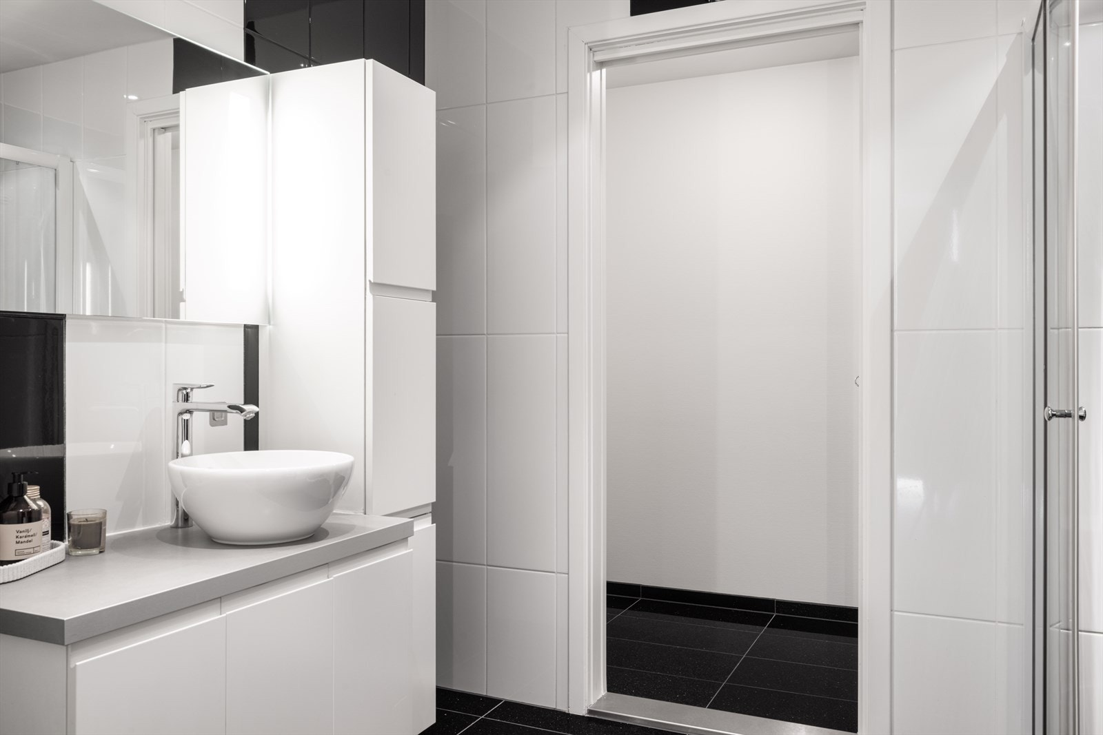 Baderommet fremstår tidløst, med lyse veggfliser som står i kontrast til mørke gulvfliser. Galleribilde