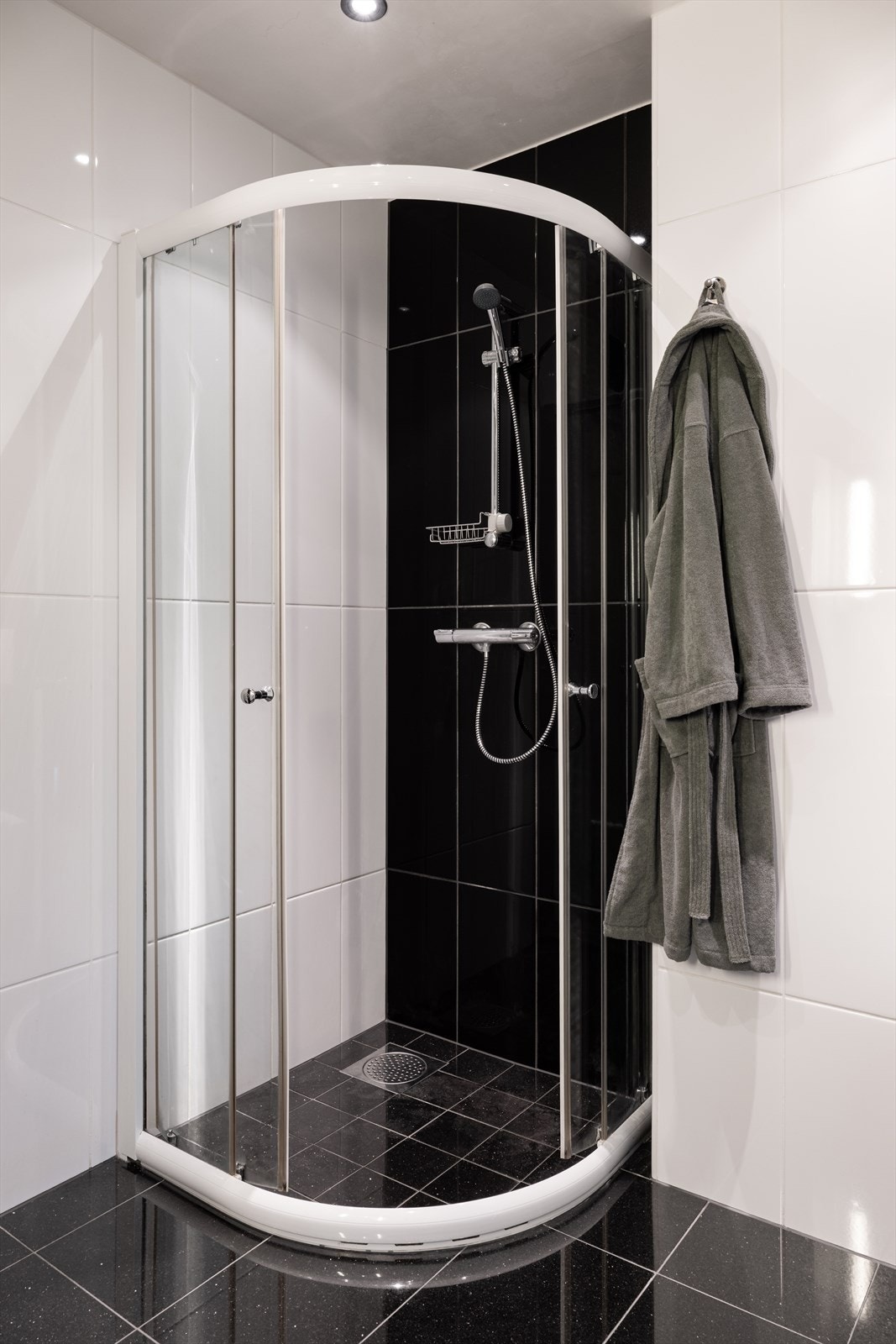 Rommet er helfliset og har vegghengt toalett, dusj, servant med underskap og overhengt speil. Galleribilde