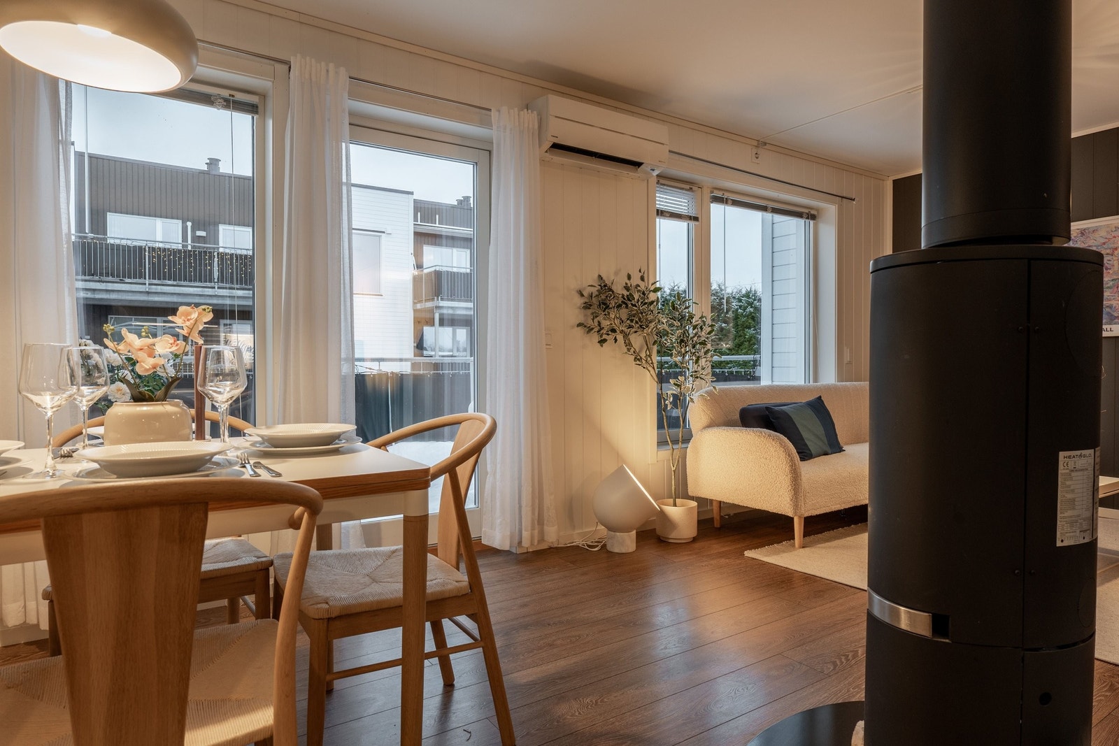 Gjennomgående lys og trivsel. De store vinduene gir et fantastisk lysinnslipp som løfter hele rommet. Her flyter sonene sømløst over i hverandre, fra spiseplassen til stuen, med peisen som en lun følgesvenn. Galleribilde