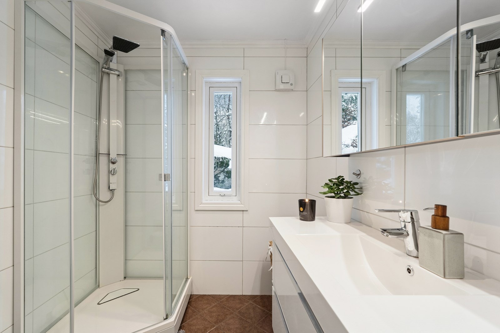 Flislagte vegger og elektriske varmekabler gir en komfortabel baderomsløsning. Dusjkabinett og servantinnredning med speilskap er inkludert. Galleribilde